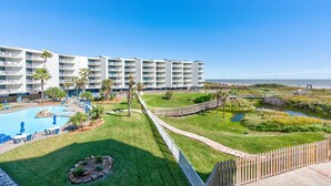 A hotel with multiple floors, a swimming pool, and a walking path. - Sandcastle Condominiums Unit 235 (Port Aransas)