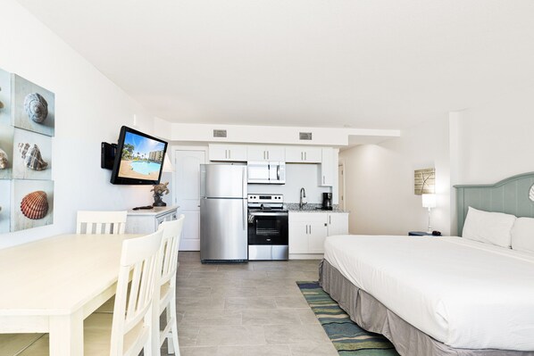 Habitació d'hotel compacta amb cuineta, zona de menjador i llit.