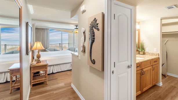 Une chambre d’hôtel avec un lit, une table de chevet, une lampe, une décoration représentant un hippocampe et une vue sur l’extérieur.