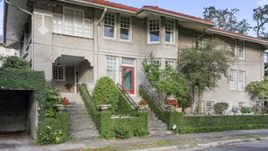 A two-story building with a red door, multiple windows, and a small front porch.