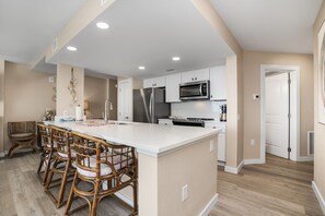 Una cocina moderna con armarios blancos, electrodomésticos de acero inoxidable y una isla central con taburetes.