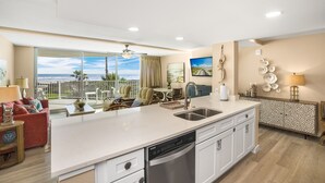 Une cuisine moderne dotée d’un grand îlot central, d’un lave-vaisselle et offrant une vue sur l’océan.