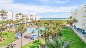 Un resort con piscina, palmeras y vista al océano.