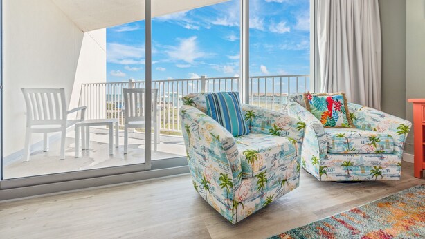 A balcony with two chairs, a white table, and a view of the sea. - Sandcastle Condominiums Unit 328 (Port Aransas)
