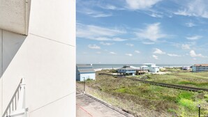 A coastal view with a train track, buildings, and a clear sky. - Sandcastle Condominiums Unit 328 (Port Aransas)
