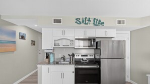 A compact kitchen with white cabinets, a stainless steel refrigerator, and a microwave.