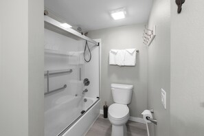 A bathroom with a bathtub, toilet, and a towel rack. - Sandcastle Condominiums Unit 332 (Port Aransas)