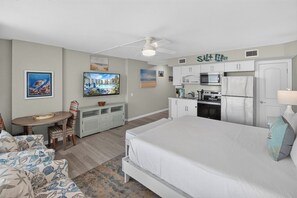 A bedroom with a bed, a desk, a chair, a television, and a kitchenette. - Sandcastle Condominiums Unit 332 (Port Aransas)