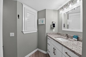 Une salle de bain avec un lavabo, un miroir et un porte-serviettes.