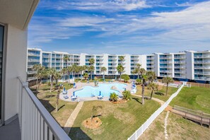 Un hotel con piscina circondata da palme e sdraio.