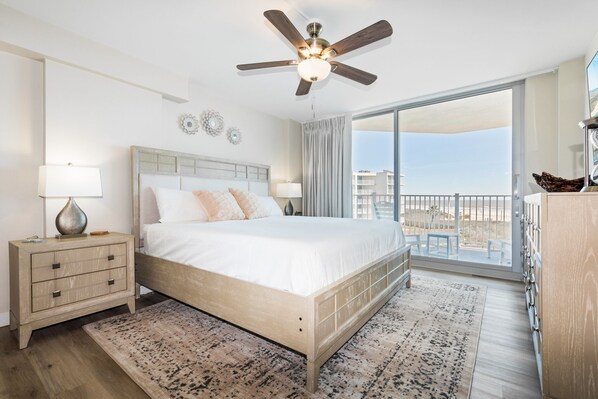 A bedroom with a bed, nightstand, dresser, and a balcony with a view.