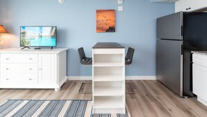 A modern kitchen with a built-in refrigerator, a TV mounted on the wall, and a white cabinet. - Sandcastle Condominiums Unit 402 (Port Aransas)
