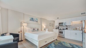 Une chambre d’hôtel moderne équipée d’un lit, d’une table de chevet, d’une lampe et d’un petit coin salon.