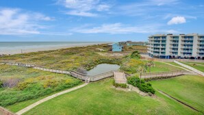 Un hôtel situé sur la côte, avec vue sur la plage, un petit étang et une promenade en bois.