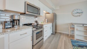 Une cuisine moderne avec des armoires blanches, des appareils en acier inoxydable et un plancher en bois.