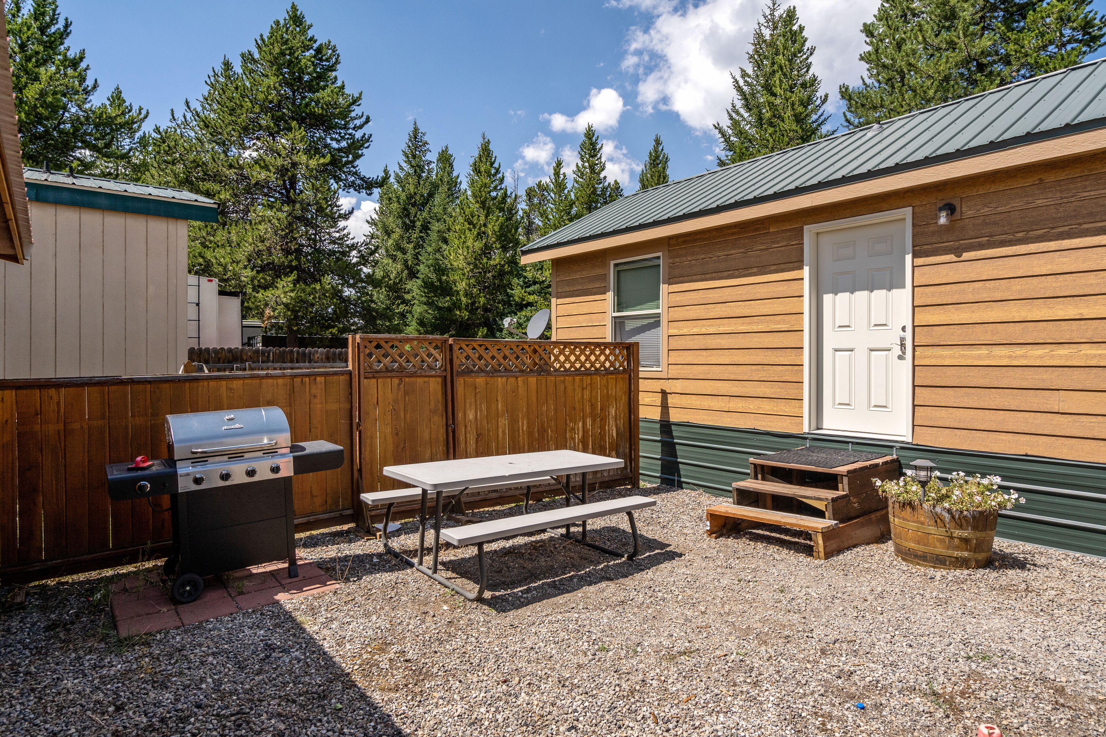 A backyard with a barbecue grill, picnic table, and wooden deck.