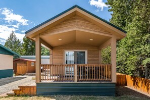 A small cabin with a wooden porch, a door, and a window. - Alpine 1 (West Yellowstone)