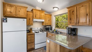 Una cocina con armarios de madera, un refrigerador blanco, estufa, microondas y cafetera.