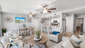 A spacious living room with a dining area, kitchen, and a view of the outdoors. - Sandcastle Condominiums Unit 404 (Port Aransas)
