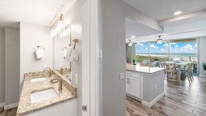 A modern kitchen with granite countertops, white cabinetry, and a large island with seating. - Sandcastle Condominiums Unit 404 (Port Aransas)