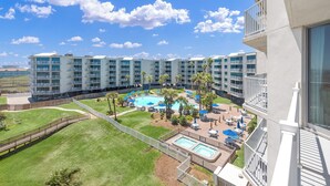 A hotel with multiple floors, a swimming pool, and outdoor seating areas. - Sandcastle Condominiums Unit 407 (Port Aransas)