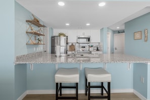 Una cocina moderna con armarios blancos, electrodomésticos de acero inoxidable y encimera de granito.