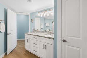 Une salle de bain avec deux lavabos, des meubles blancs et un grand miroir avec éclairage intégré.