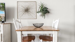 A dining table with two white chairs, a wooden top, and a black bowl. - Sandcastle Condominiums Unit 410 (Port Aransas)