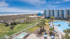 A resort with a pool, beach view, and a building with multiple balconies. - Sandcastle Condominiums Unit 415 (Port Aransas)