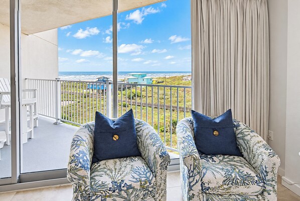 A balcony with two chairs, a view of the ocean, and a railing. - Sandcastle Condominiums Unit 428 (Port Aransas)