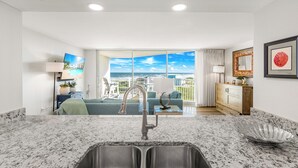 A kitchen with a large window, a sink, and a view of the ocean. - Sandcastle Condominiums Unit 430 (Port Aransas)