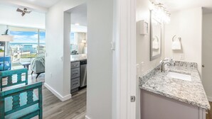 A modern kitchen with a granite countertop, a built-in dishwasher, and a view of the balcony. - Sandcastle Condominiums Unit 430 (Port Aransas)
