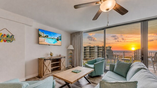 A modern living room with a large window, a ceiling fan, a wooden coffee table, and a sofa.