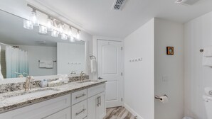 A bathroom with a white vanity, a large mirror, and a shower area.