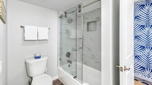 A modern bathroom with a glass-enclosed shower, a toilet, and a bathtub. - Sandcastle Condominiums Unit 502 (Port Aransas)