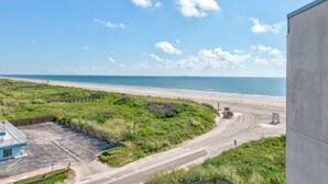 A coastal view with a beach, a parking area, and a building. - Sandcastle Condominiums Unit 502 (Port Aransas)