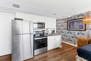 A modern kitchen with stainless steel appliances, white cabinetry, and a patterned wall. - Sandcastle Condominiums Unit 502 (Port Aransas)