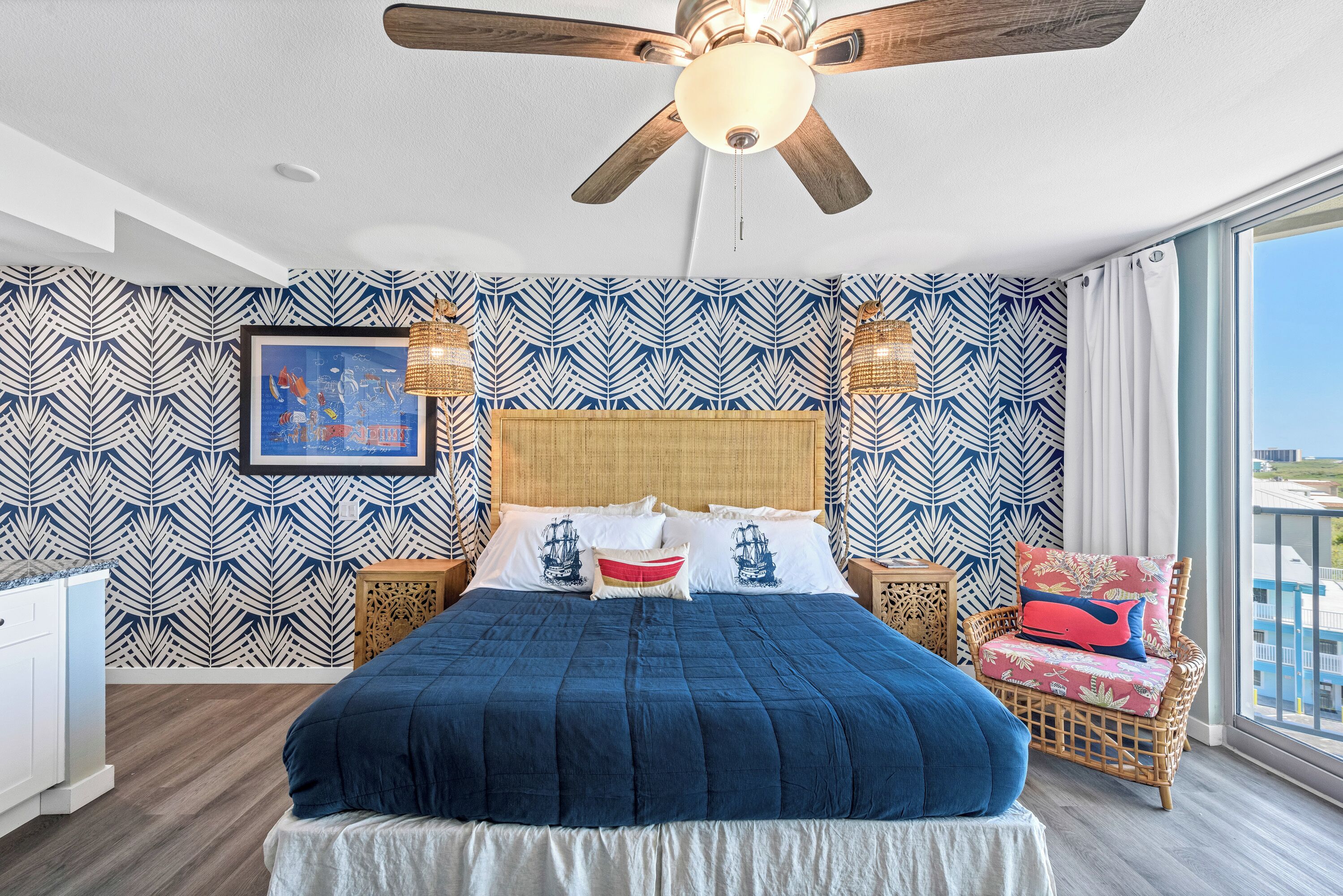 A bedroom with a large bed, a ceiling fan, and a view of the city.
