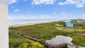 A coastal view with a beach, a wooden boardwalk, and a small pond. - Sandcastle Condominiums Unit 503 (Port Aransas)