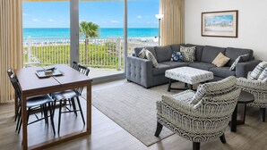 A living room with a sofa, chairs, a dining table, and a view of the ocean. - Sandcastle Condominiums Unit 518 (Port Aransas)