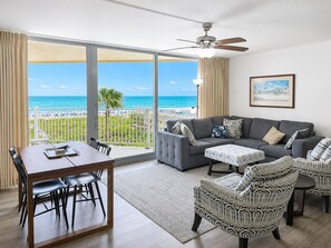 A living room with a sofa, chairs, a dining table, and a view of the ocean. - Sandcastle Condominiums Unit 518 (Port Aransas)