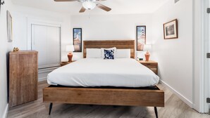 Une chambre à coucher avec un lit en bois, un ventilateur de plafond et deux lampes de chevet.