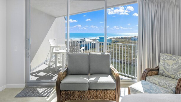 Een balkon met uitzicht op de oceaan, een rieten stoel en een comfortabele zithoek.