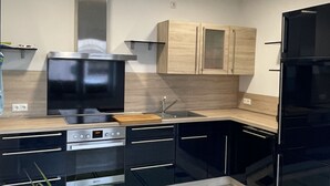Une cuisine moderne avec des appareils électroménagers noirs, des meubles en bois et un tapis vert.