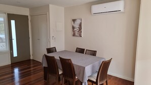 A dining area with a rectangular table, six wooden chairs, and a grey tablecloth. - Beaton's Beach Front Studio - Inverloch (Inverloch)