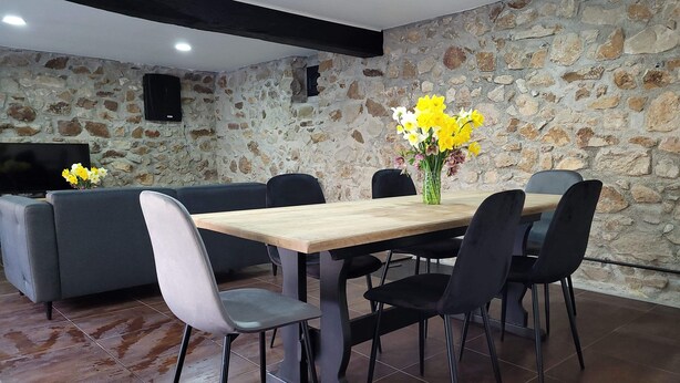 A dining area with a stone wall, a wooden table, and black chairs. - House near nogent sur Seine (Crancey)
