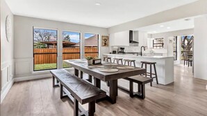 Une cuisine moderne dotée d’un îlot central, de grandes fenêtres et donnant sur le jardin.