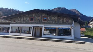 Un bâtiment à la façade traditionnelle, avec un commerce au rez-de-chaussée et une chaîne de montagnes en arrière-plan.