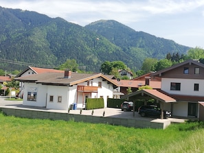 Un quartier résidentiel avec des maisons, un petit bâtiment portant une enseigne, et une montagne en arrière-plan.