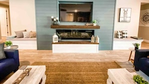 A living room with a fireplace, a sofa, a coffee table, and a TV mounted above the fireplace.